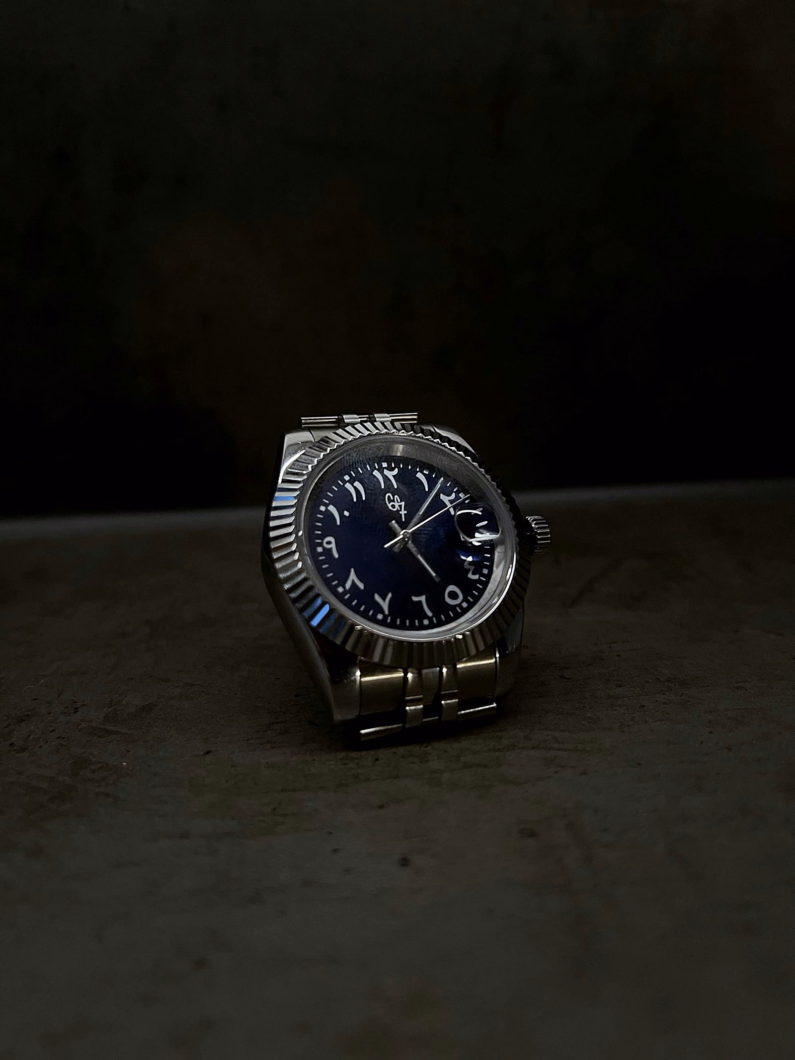 Azure by 6F7, its blue dial and silver-toned bracelet emerging from shadow.